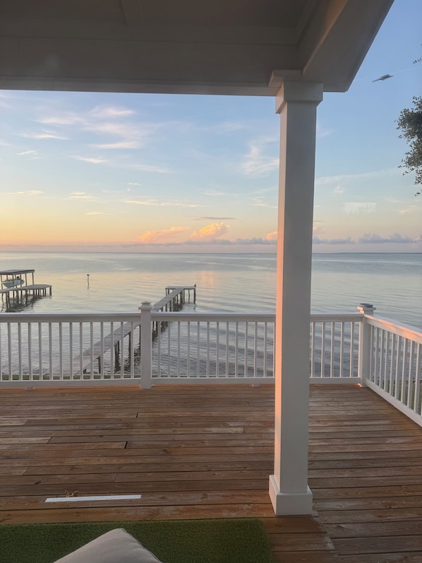 A wooden deck with a railing, a covered area, and a view of the water. - Waterfront Gulf 3 BR Home Ocean Springs MS - Sleeps 7 - Coastlines & Sunsets (Ocean springs)
