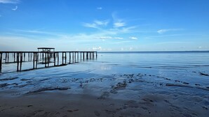Una playa con un muelle de madera que se adentra en aguas tranquilas.