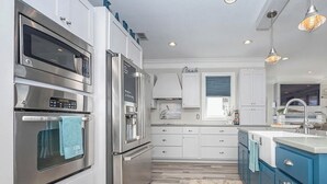 Una cocina moderna con electrodomésticos integrados, un ventanal grande y una pared de acento azul.
