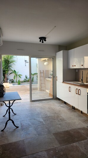 A modern kitchen with a sliding glass door leading to a patio area. - House within walls Aigues-Mortes (Aigues-Mortes)