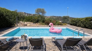 Una piscina con sillas de descanso y un flotador con forma de flamenco rosa.