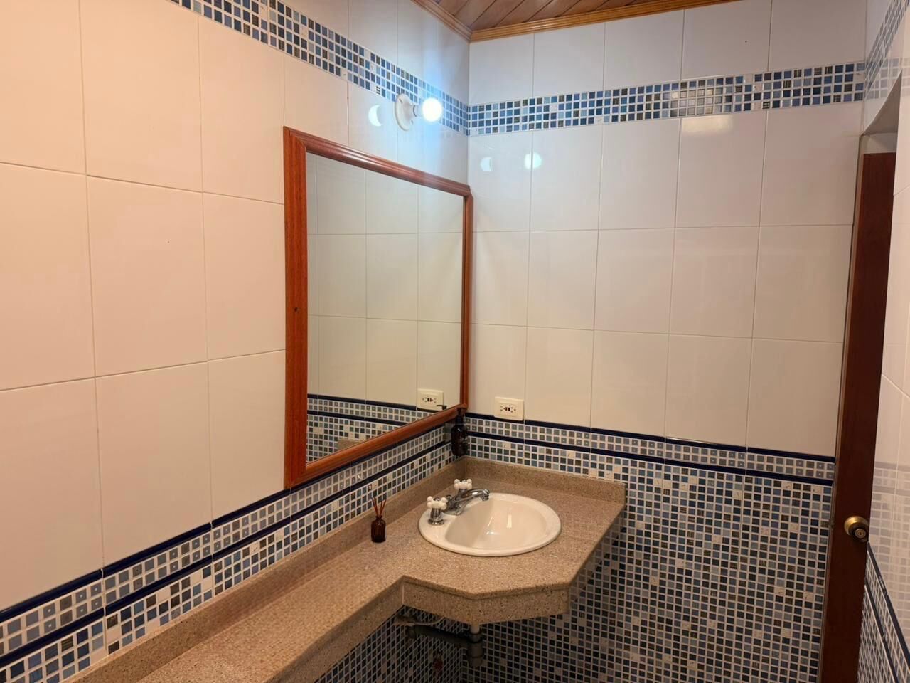 Un baño con lavabo, espejo y paredes de azulejos.