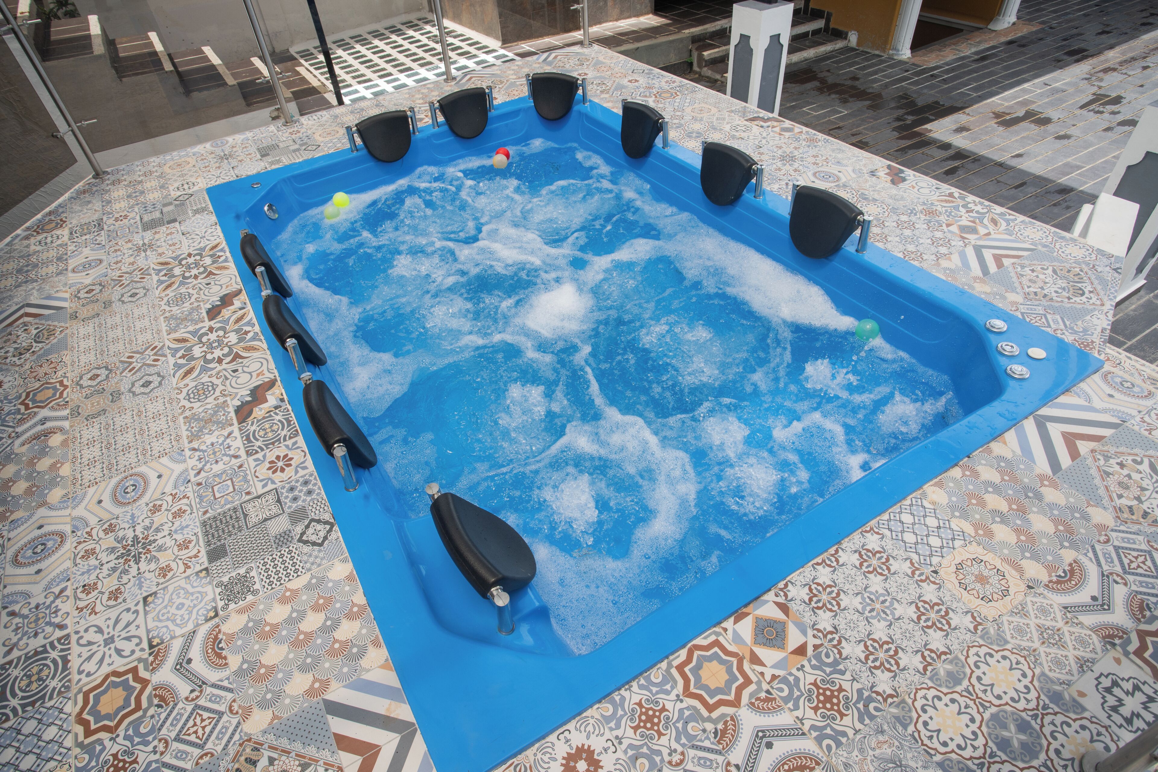 Un jacuzzi con cubierta azul, rodeado de baldosas estampadas.