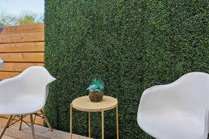 Eine Holzterrasse mit zwei wei ßen Stühlen und einem kleinen runden Tisch mit einer Ananas als Mittelstück.
