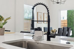 Eine moderne Küche mit Spüle aus Edelstahl, Armatur in Schwarz und Marmorarbeitsplatte.