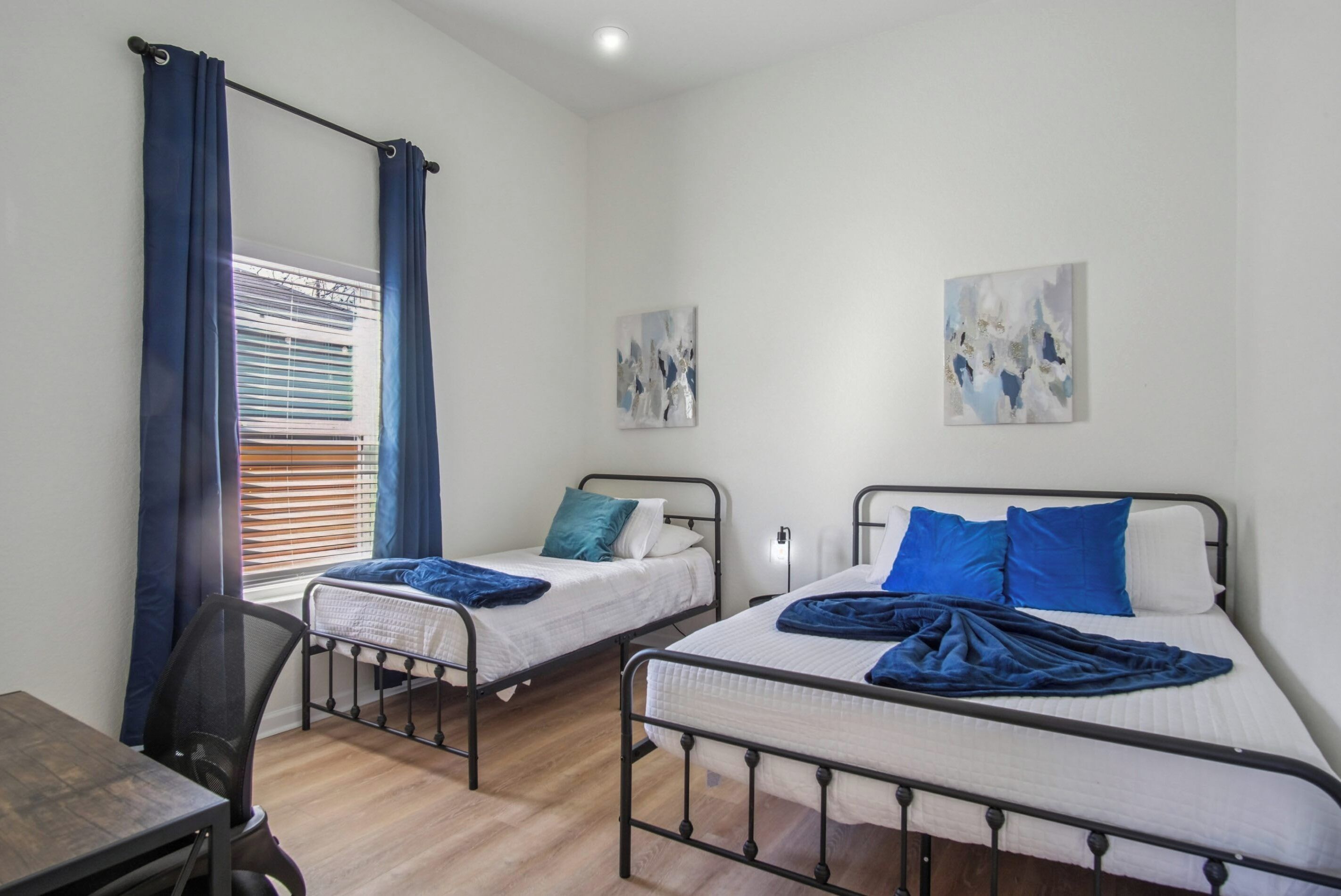 Quarto com duas camas individuais, uma escrivaninha e uma cadeira.