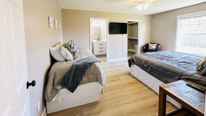 Ein Schlafzimmer mit Bett, Schreibtisch, Kleiderschrank und Deckenventilator.