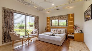 Un dormitorio con cama, una silla, una mesita de noche y una ventana con cortinas.