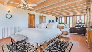 A spacious bedroom with a large bed, a wooden bench, a ceiling fan, and a view of the outdoors. - Mallorca Finca Aria vacation home a quiet paradise for family & friends (Búger)