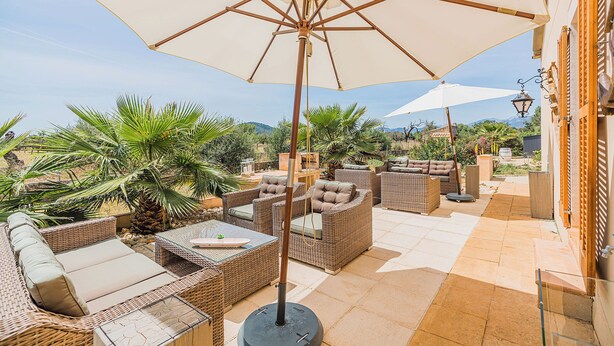 A patio with wicker furniture, a large umbrella, and a view of the mountains. - Mallorca Finca Aria vacation home a quiet paradise for family & friends (Búger)