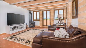 A living room with a large flat-screen TV, leather sofa, and a fireplace. - Mallorca Finca Aria vacation home a quiet paradise for family & friends (Búger)