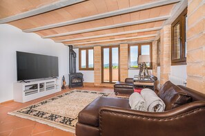 Ein Wohnzimmer mit großem Flachbildfernseher, Ledersofa und Kamin.