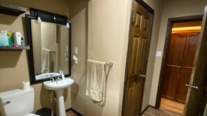 Un baño con inodoro, lavamanos, espejo y toallero.