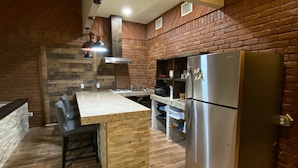 Una cocina con una isla de madera, un refrigerador de acero inoxidable y una pared de ladrillo.