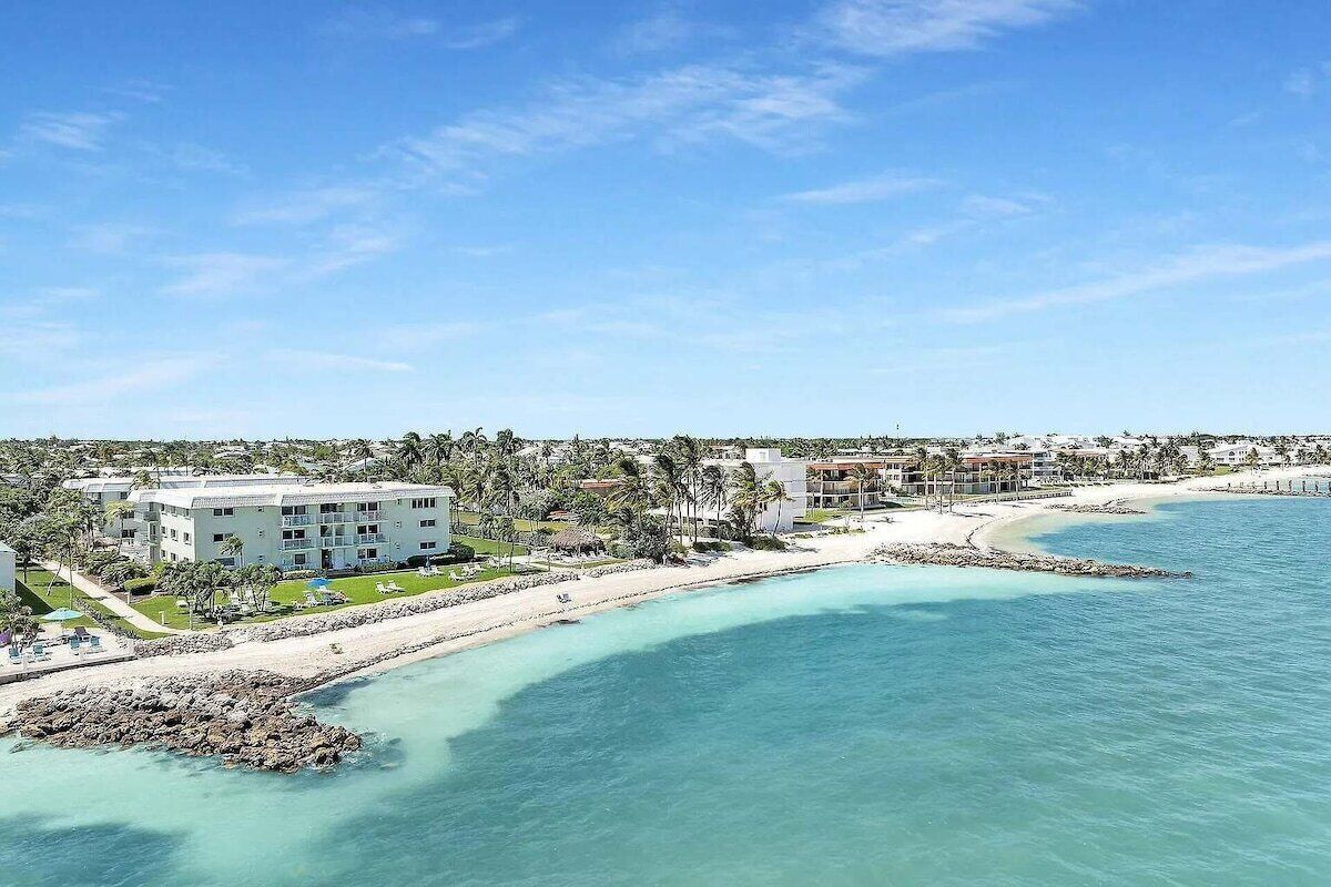 Um hotel à beira-mar, com vista para a praia, vários edifícios e céu claro.
