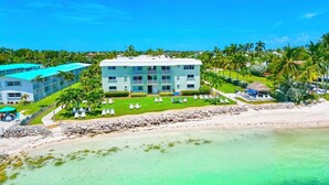 Un hôtel situé en bord de mer, doté d’une piscine, de chaises longues et offrant une vue dégagée sur l’océan.