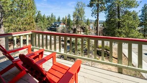 Una terraza de madera con sillas rojas, con vistas a una zona residencial con casas y árboles.