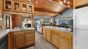 Una cocina con armarios de madera, un refrigerador blanco y una zona de comedor con sofá y mesa.