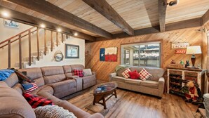 Ein gemütliches Wohnzimmer mit Holzboden, einer Treppe, einer Sofagarnitur, einem Couchtisch sowie einer Wand mit einer Texas-Flagge und Angelzierdekor.
