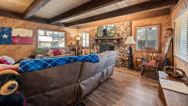 Ein rustikales Blockhaus-Interieur mit Kamin aus Stein, Holzbalken, einer Couch und einer Flagge als Dekoration.