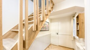 Een trap met houten leuningen die uitkomt op een plateau, een witte deur en een raam met uitzicht.