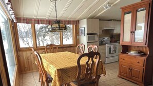 Un comedor con mesa y sillas, una cocina con electrodomésticos y un armario con espejo.