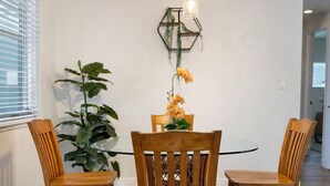 Un comedor con una mesa de vidrio, sillas de madera, un tapete estampado y una lámpara colgante.