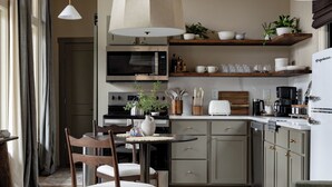 A modern kitchen with a dining area, wooden furniture, and pendant lighting. - Cabin w/ Sauna + Hot Tub - Luxury Woods Retreat (Logan)