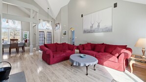 A spacious living room with a high ceiling, a dining area with natural light, and a large window. - Hot Tub*Sauna*Pool Table*Air Hockey*King Bed*Deck (Blakeslee)