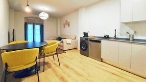 A compact living space with a dining area, sofa, washing machine, and kitchenette. - Apt. 1 br. Cathedral I, Historic Center (Valladolid)