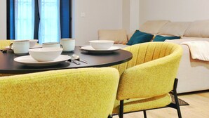 A dining area with yellow chairs, a round table, white bowls, and plates. - Apt. 1 br. Cathedral I, Historic Center (Valladolid)