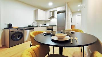 Una cocina compacta con lavadora, microondas y comedor con mesa y sillas.
