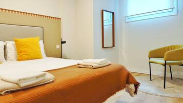 Een hotelkamer met een bed, een stoel, een raam en een spiegel.