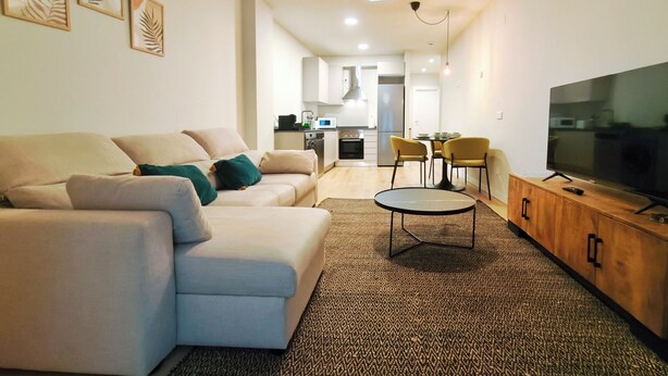 A modern living room with a sofa, a coffee table, a TV, and a kitchen in the background. - Apt. 1 br. Cathedral I, Historic Center (Valladolid)