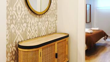 Un baño con pared estampada, un espejo redondo y un tocador de madera.