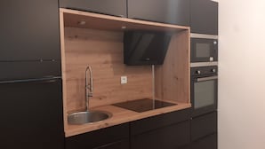 Une cuisine dotée d’un plan de travail en bois, d’un évier en acier inoxydable et d’un micro-ondes noir.