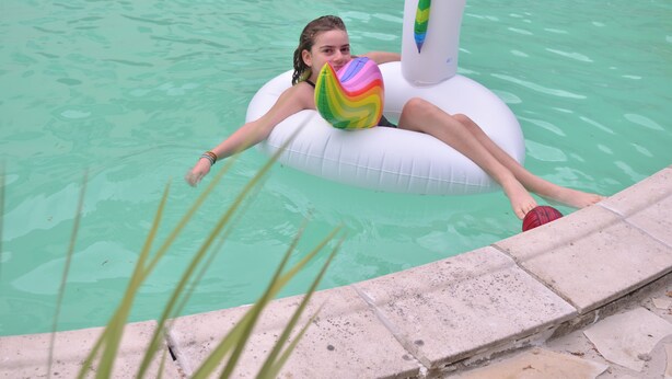 Une personne flottant sur un matelas gonflable pour piscine, orné d’un motif coloré.