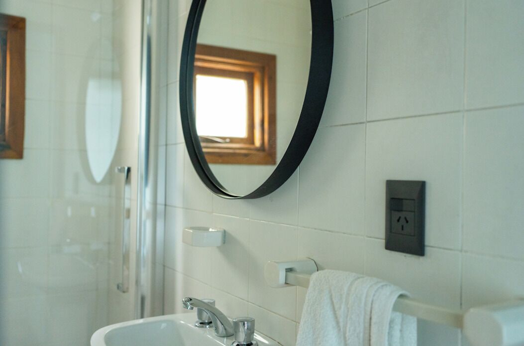 A bathroom with a large mirror, a sink, a towel rack, and a window with a view.