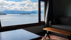 A room with a large window, a bed, a small table, and a patterned rug. - Casa Siete - Your home in Bariloche (San Carlos de Bariloche)