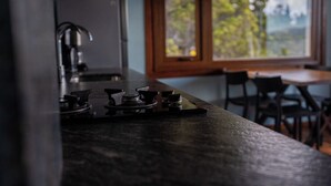 A kitchen with a stove, a refrigerator, and a window with a view of trees. - Casa Siete - Your home in Bariloche (San Carlos de Bariloche)