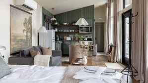 A modern living room with a sofa, a coffee table, and a dining area with a table set for two. - Modern Couples Cabin - Hot Tub + Outdoor Shower (Logan)