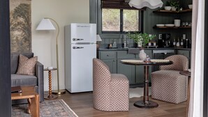 A compact kitchen with a refrigerator, a dining table, two chairs, a sofa, and a lamp. - Modern Couples Cabin - Hot Tub + Outdoor Shower (Logan)
