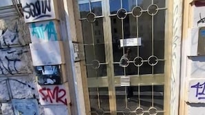 Ingresso di un edificio con cancello in metallo, pareti in pietra e graffiti.