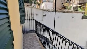 Un balcone stretto con pavimento in piastrelle e ringhiera in metallo nero.