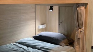A single bed with a headboard, a bedside table, a power outlet, and a curtain. - Room-charming B&B Retreat in Vibrant Phr (Bangkok)