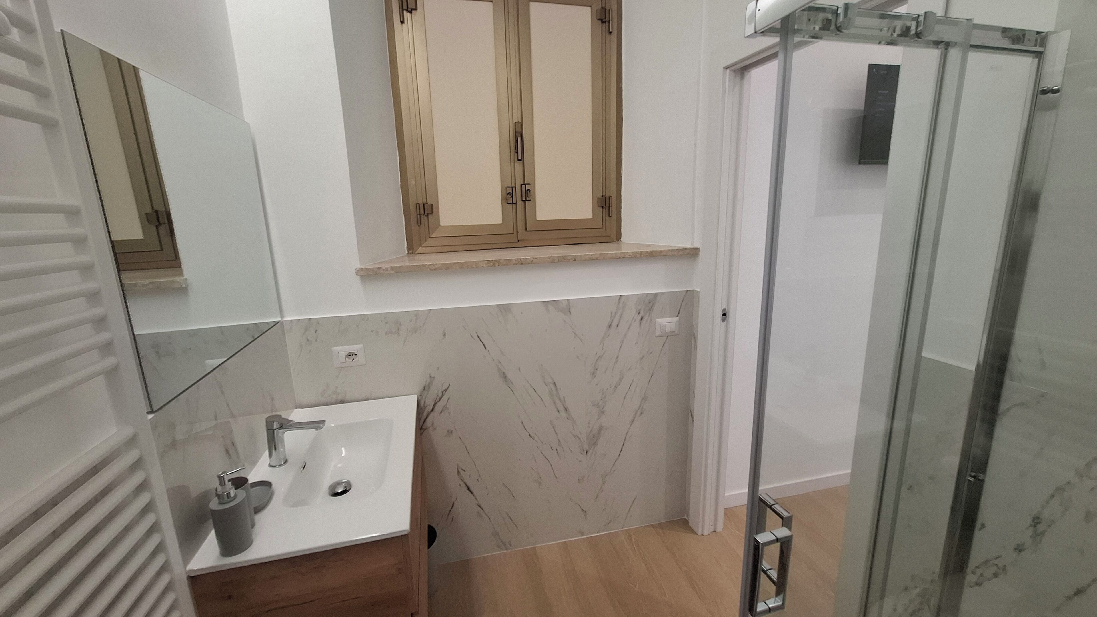 A bathroom with a sink, mirror, cabinet, and shower.