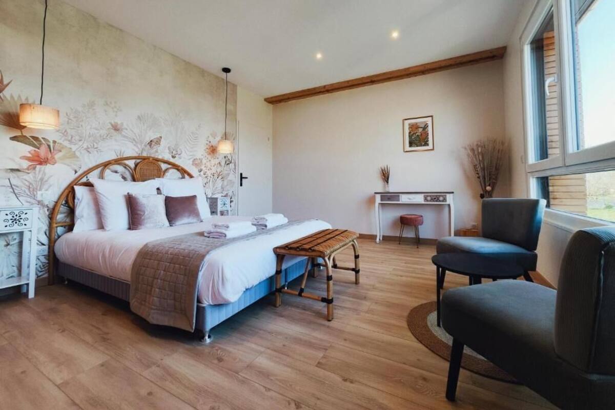 A bedroom with a bed, bedside tables, a desk, a chair, and a window.