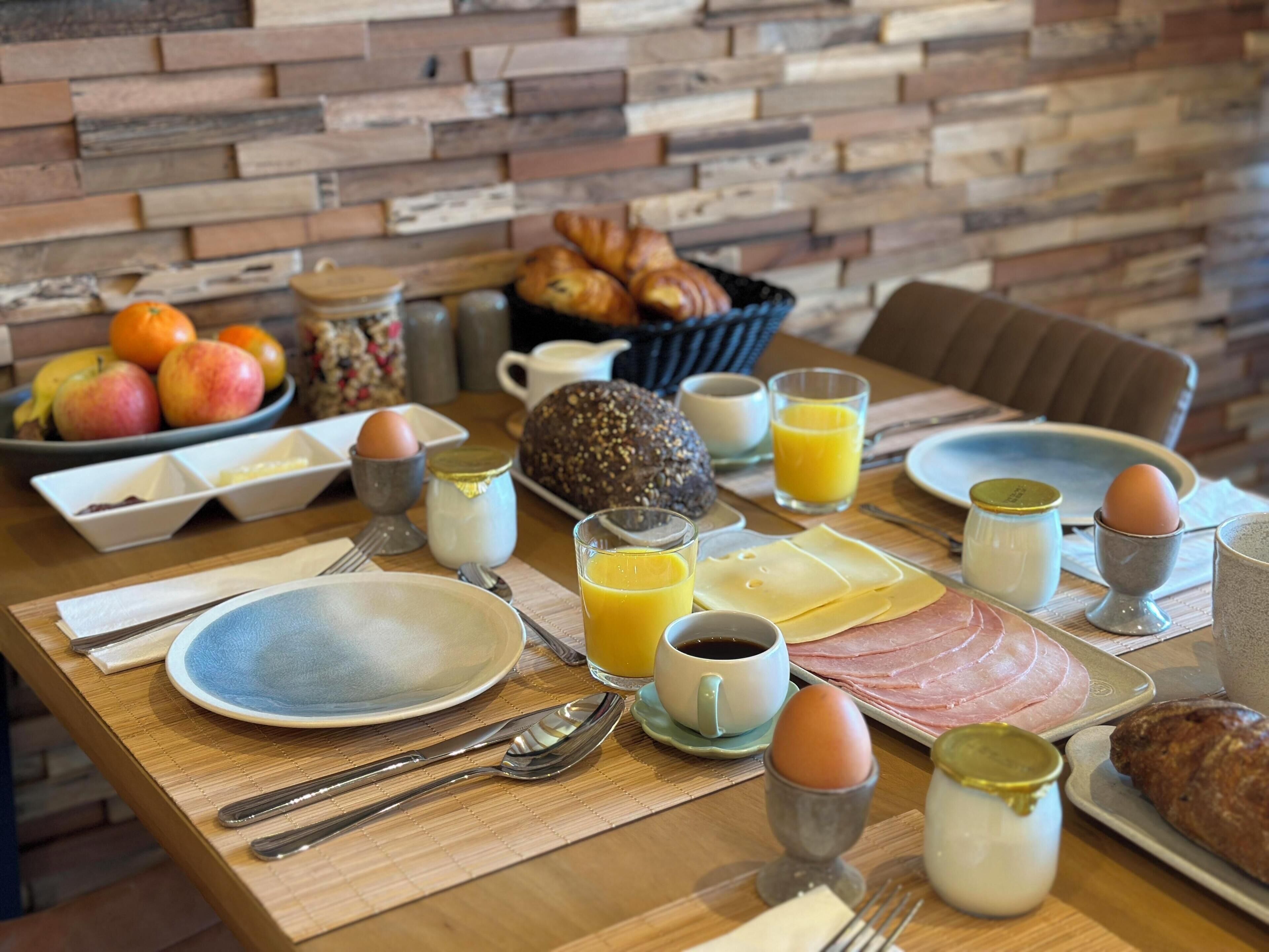 A breakfast table with eggs, bread, fruits, and juice.