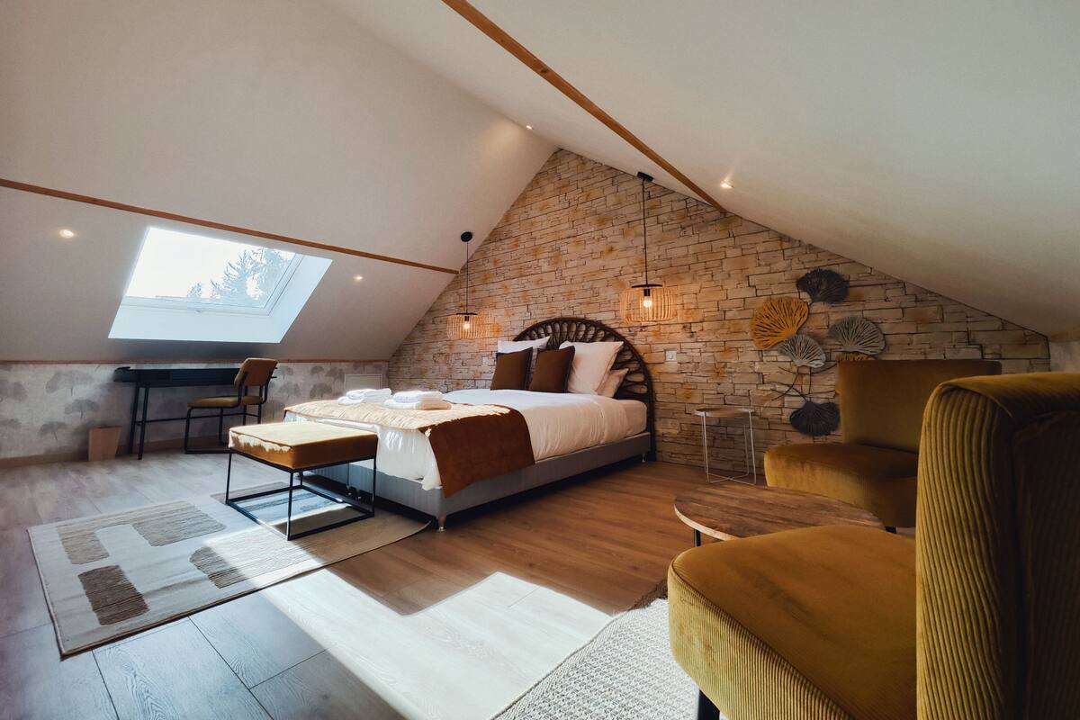 A bedroom with a sloped ceiling, a bed, a desk, and a chair.