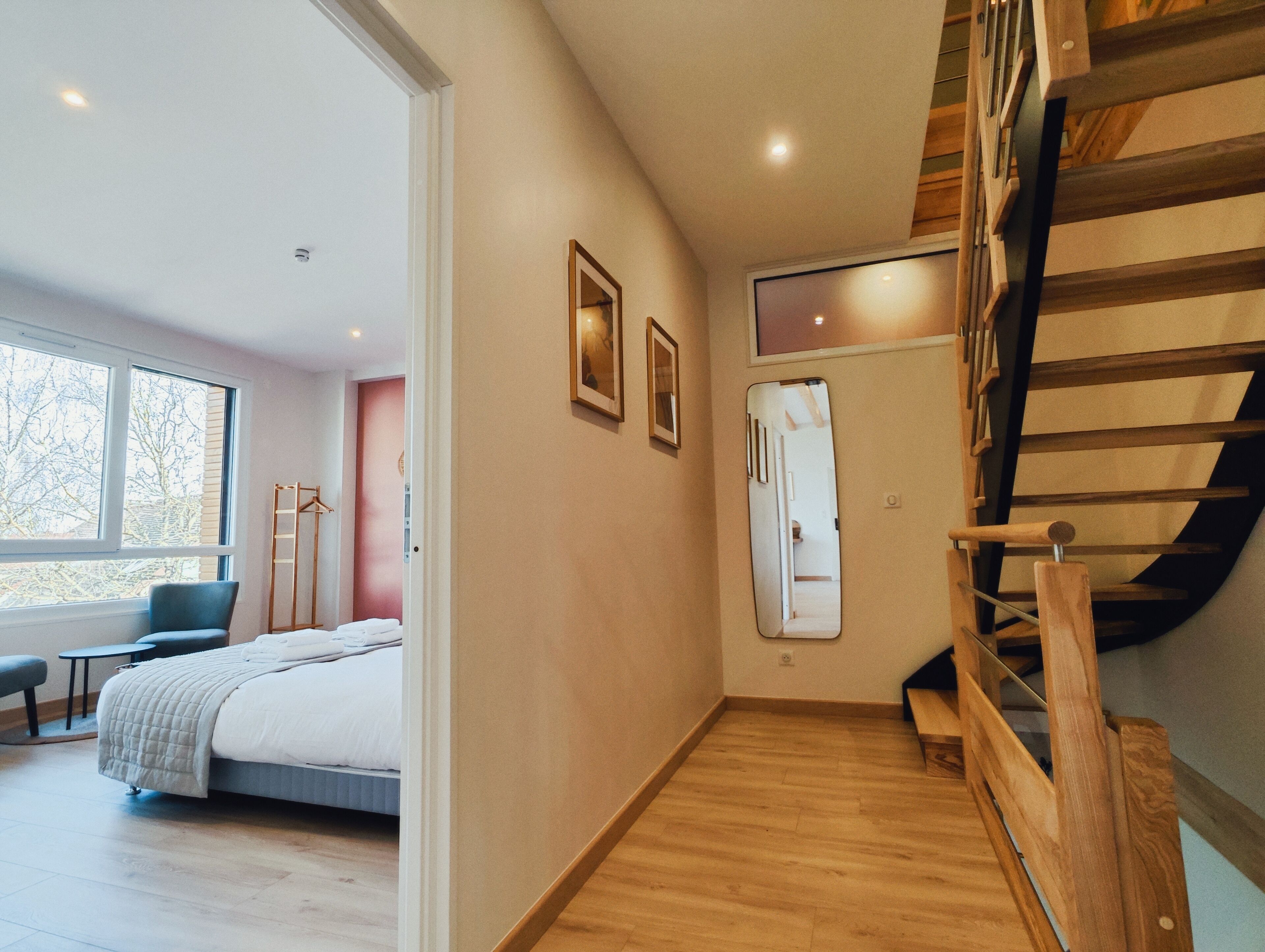 Une chambre d’hôtel moderne équipée d’un lit, d’un bureau, d’une chaise, d’un miroir et d’un escalier.